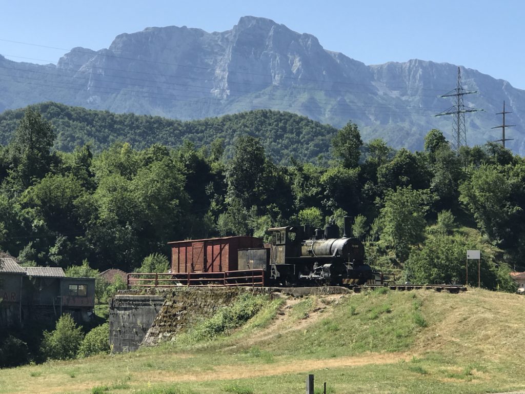 Majestic mountains tower over the old train on display in Jablanica's Bridge of Neretva in Bosnia.