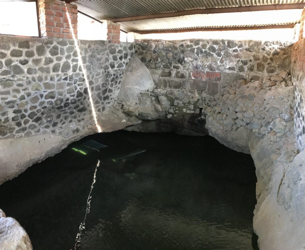 The covered structure with sparkling clean water. It looks like a big well that collects rain water for drinking and cooking.