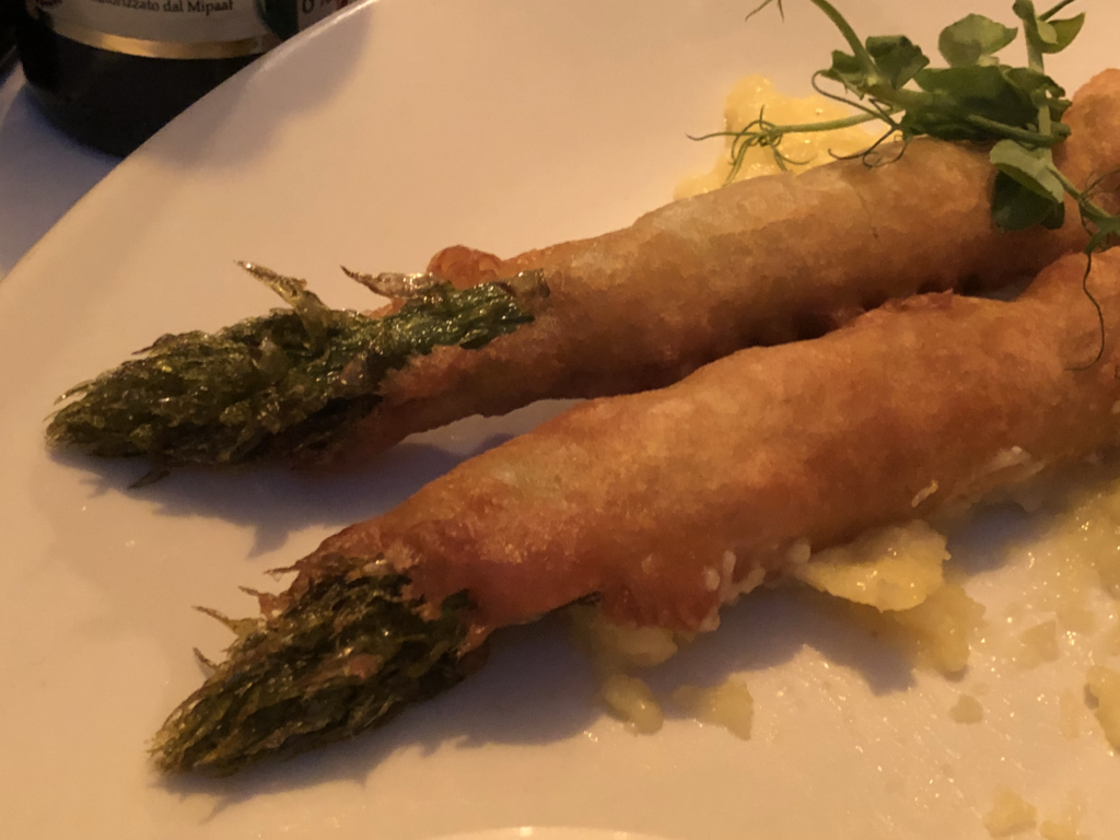 Asparagus rolled in blankets with pea shoots and some sauces.