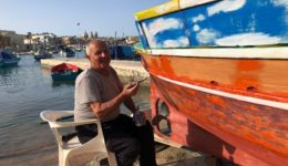 A fisherman in Marsaxlokk painting his boat.