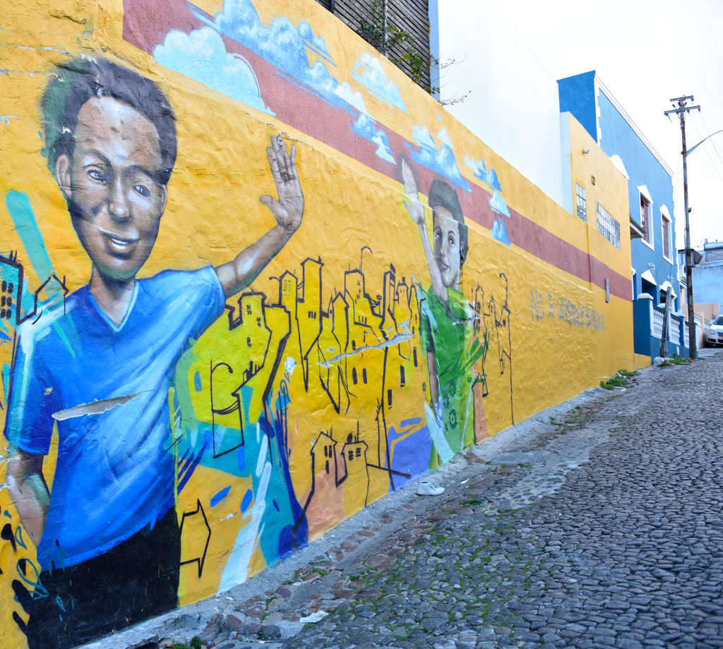 A black and white kid are high-fiving in Bo-Kaap.