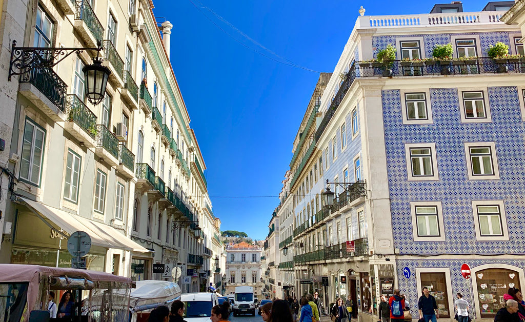 A quintessential Lisbon street with Portuguese tiled buildings and matching balconies.