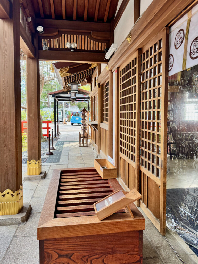 Beautiful wooden donation box and traditional checkered sliding doors at the main shrine at Atago Jinja in Tokyo