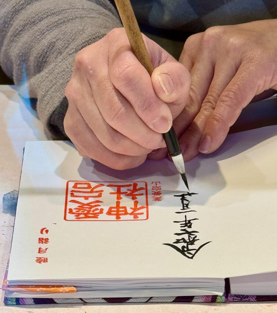 A priest writing a Goshuin message in goshuincho book at Atago Jinja Tokyo.