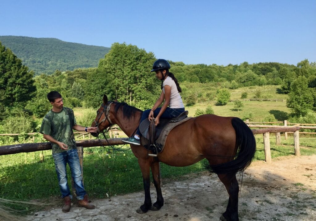 Returning from a horseback ride through green countryside hills near Plitvice Lakes National Park in Croatia on a sunny summer morning.