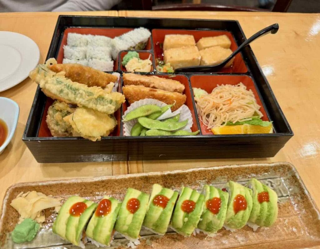A Japanese vegan meal - extensive and colorful bento box and sushi topped with avocado and sauce in Ann Arbor, Michigan