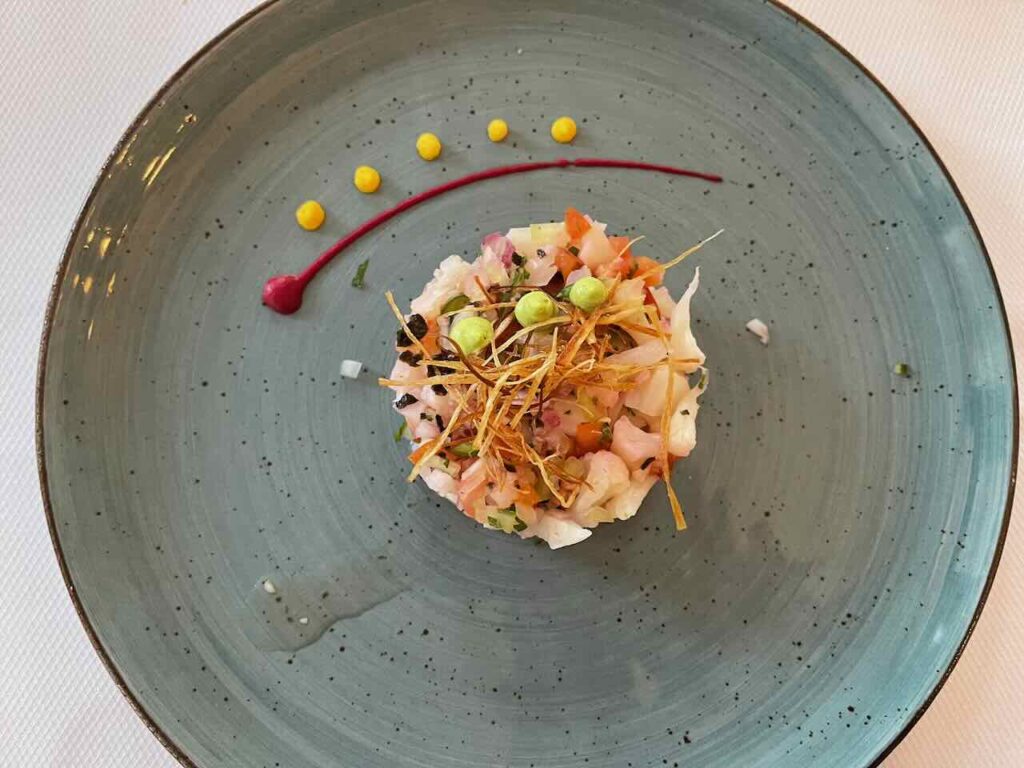 Modern Mexican salad of finely chopped vegetables stack and decorated with a sauce streek