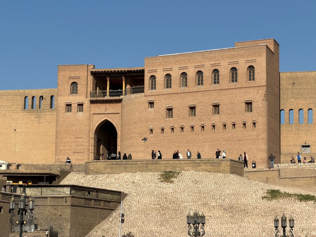 The main entrance gate of the Erbil Citadel with visitors walking along the top of the ancient brick walls, Iraqi Kurdistan