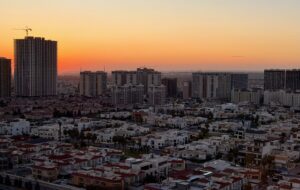 Erbil city skyline glowing orange at sunset with minarets and modern buildings visible, Iraqi Kurdistan