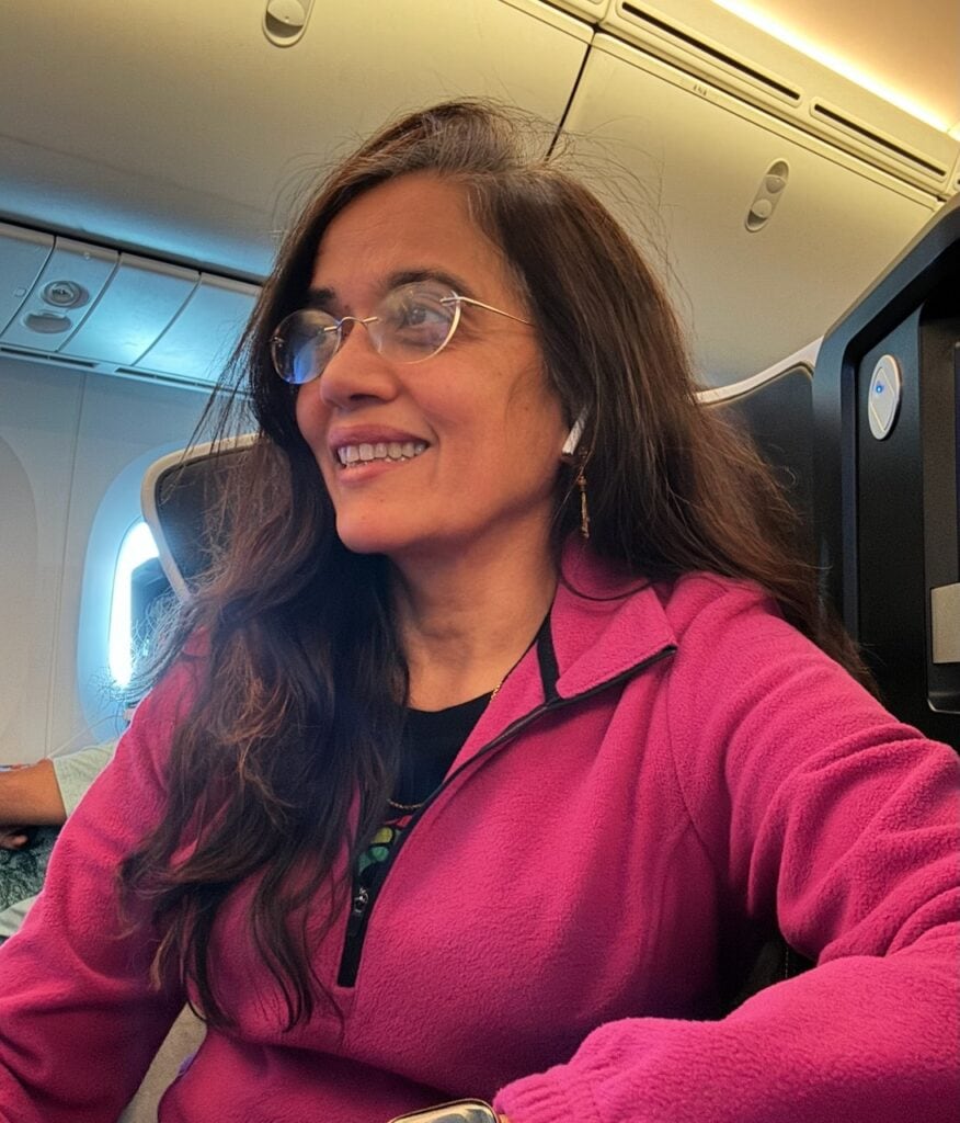 Jyoti Baid relaxed and settled in on a long-haul business class flight wearing a pink fleece