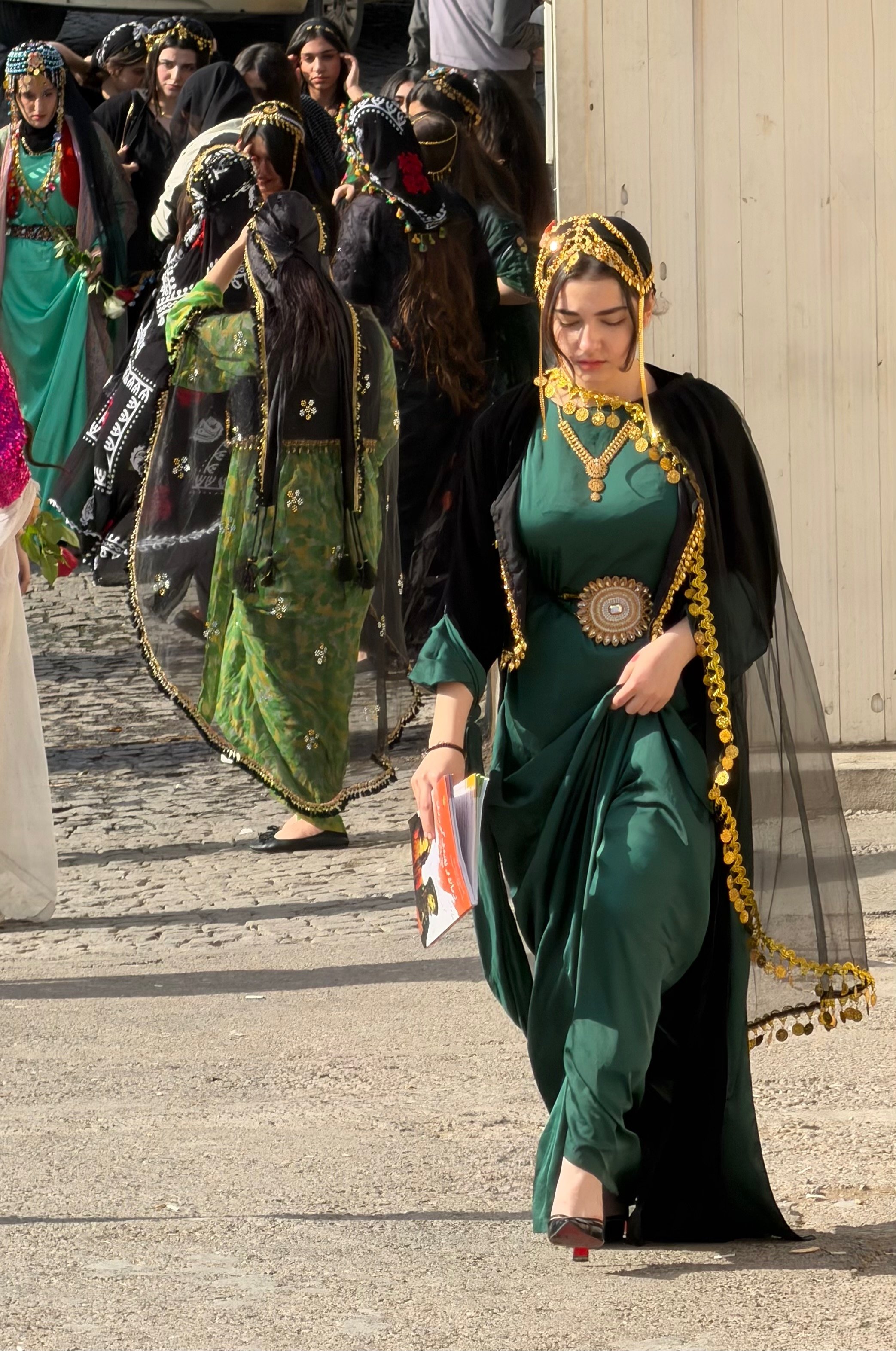 Kurdish women in traditional ceremonial green and black dress with elaborate gold coin headdresses and jewellery walking in Erbil, Iraqi Kurdistan
