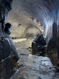 Looking into the entrance of the underground Lalish oil chamber, with blackened clay oil pots lining the stone shelves on both sides, Iraqi Kurdistan