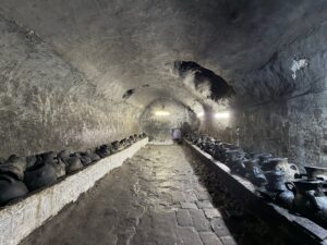 Stone-vaulted tunnel of the sacred oil storage chamber beneath the Lalish temple, lined with rows of ancient blackened clay pots used for holy olive oil, Iraqi Kurdistan