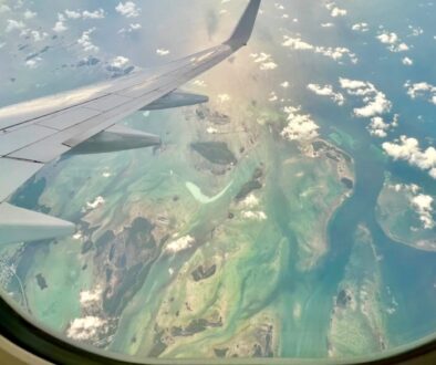 Aerial view of Key West, Florida from a long-haul flight window, showing turquoise waters and island chains