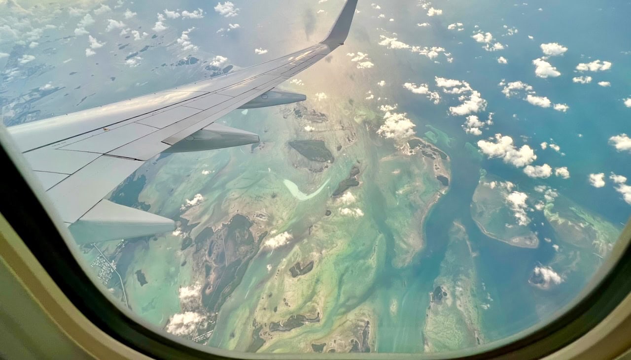Aerial view of Key West, Florida from a long-haul flight window, showing turquoise waters and island chains