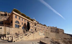 The facade of Mar Mattai Monastery with a prominent cross against a deep blue sky, northern Iraq