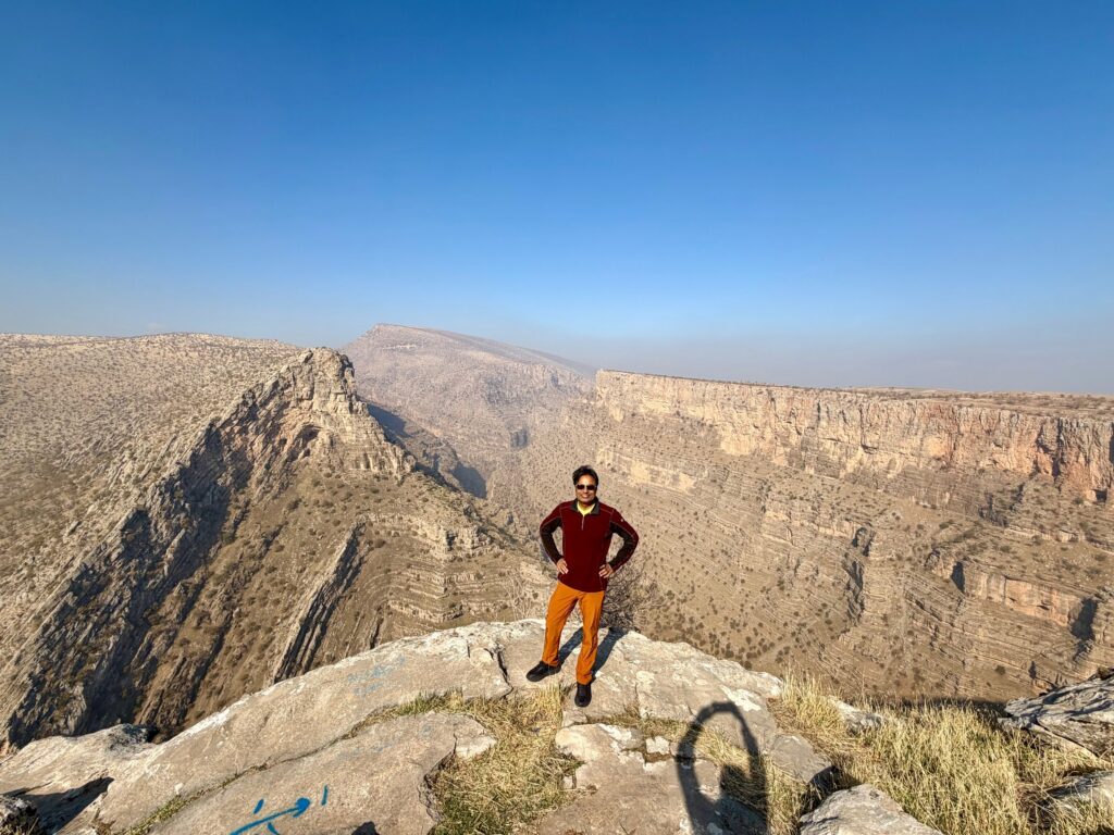 Nirmal standing at the rim of Rawanduz Canyon overlooking the deep gorge and river below, Iraqi Kurdistan