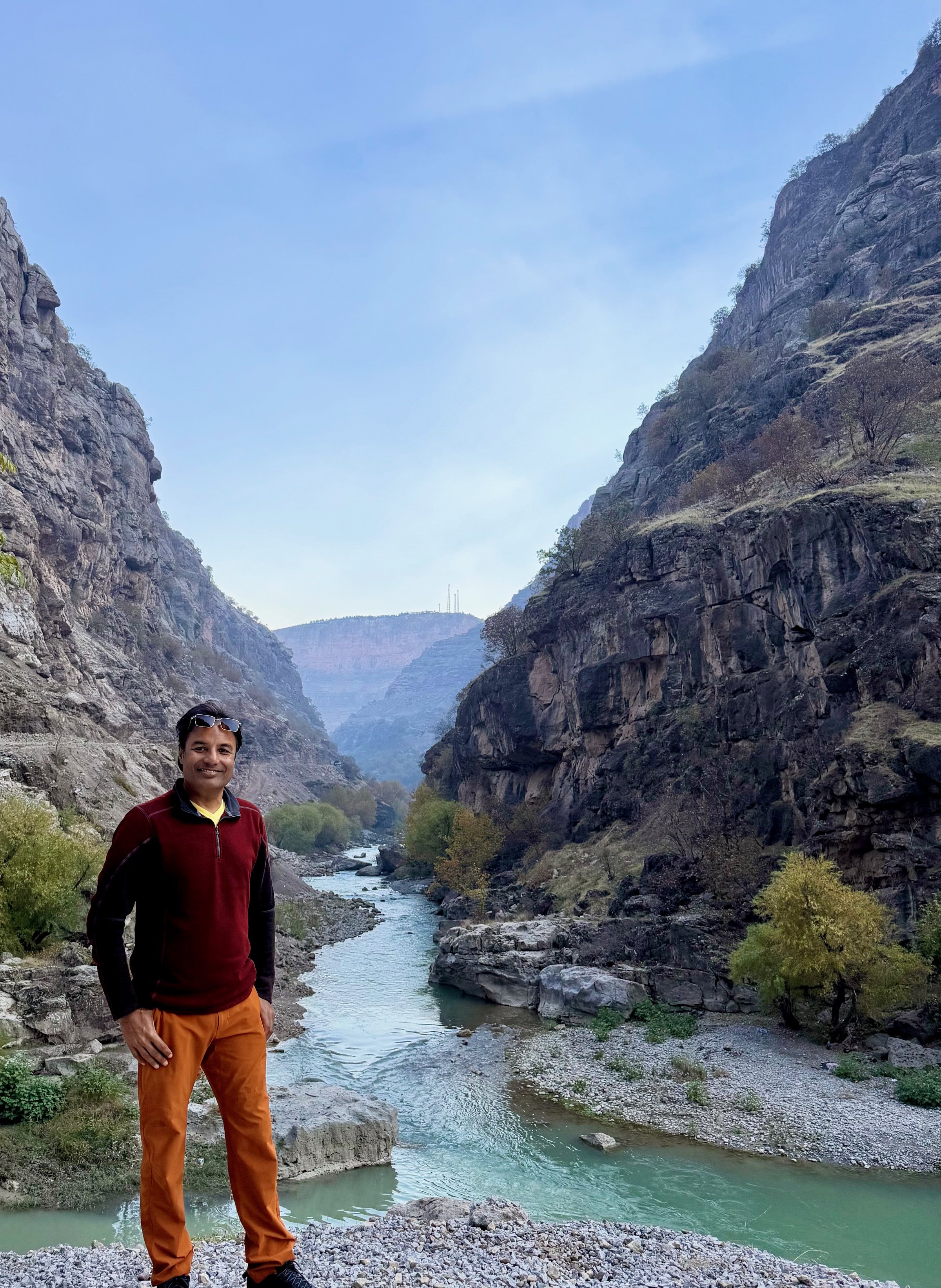 Nirmal standing beside the Rawanduz River at the base of the canyon walls, Iraqi Kurdistan
