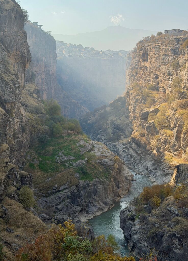 Aerial view of Rawanduz Canyon with a turquoise river winding through a deep limestone gorge in morning mist, Iraqi Kurdistan