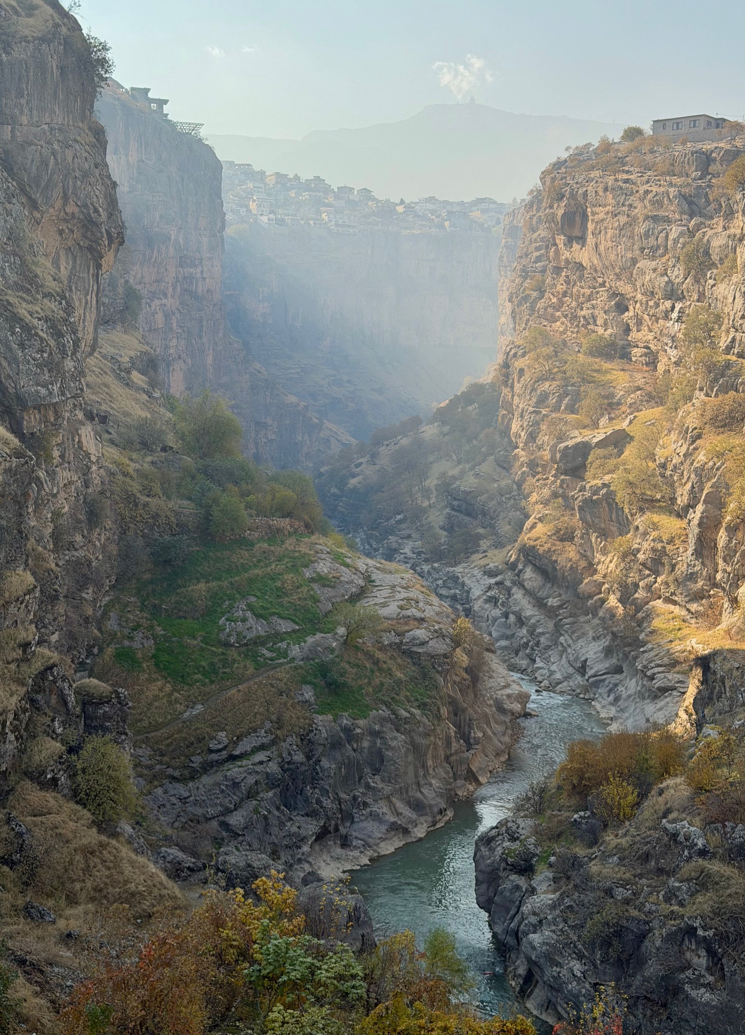 Aerial view of Rawanduz Canyon with a turquoise river winding through a deep limestone gorge in morning mist, Iraqi Kurdistan