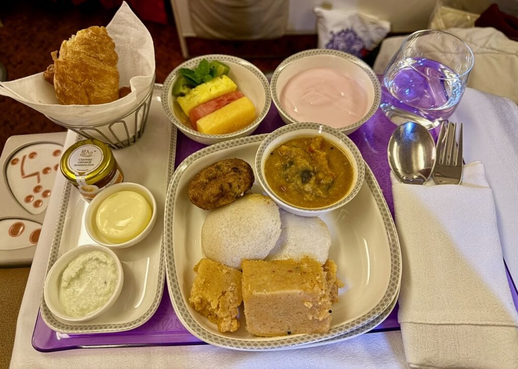 Pre-ordered vegan Indian breakfast on a long-haul flight featuring idli, sambar, coconut chutney, fresh fruit and yogurt