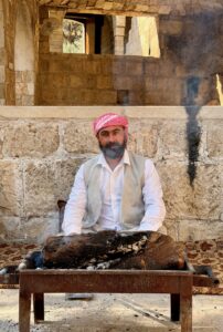 A Yazidi guardian in white robes tending a ceremonial flame at the Lalish temple, Iraqi Kurdistan