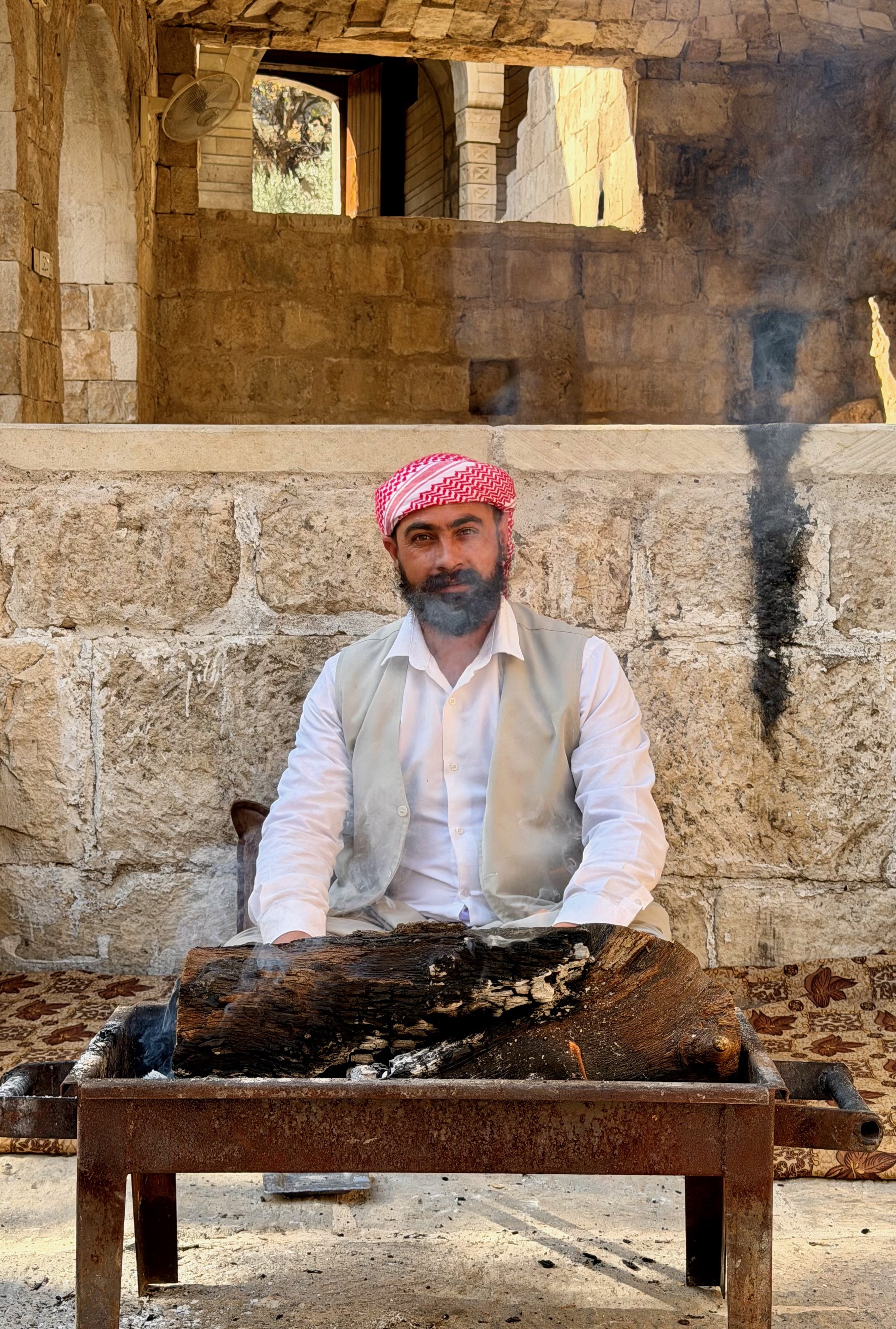 A Yazidi guardian in white robes tending a ceremonial flame at the Lalish temple, Iraqi Kurdistan