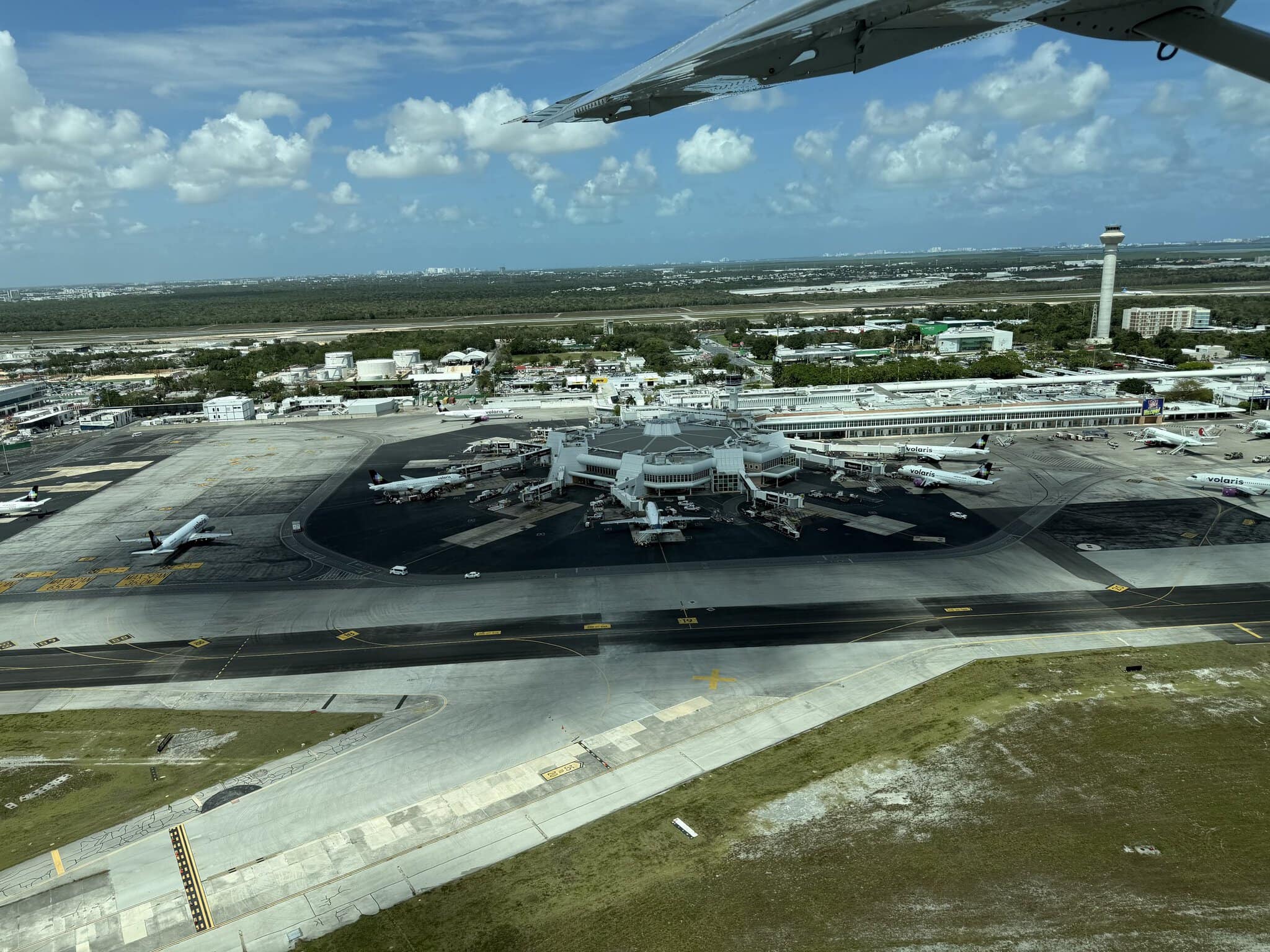 Aerial view of Cancun International Airport departing for Belize City, showing the terminal and multiple aircraft