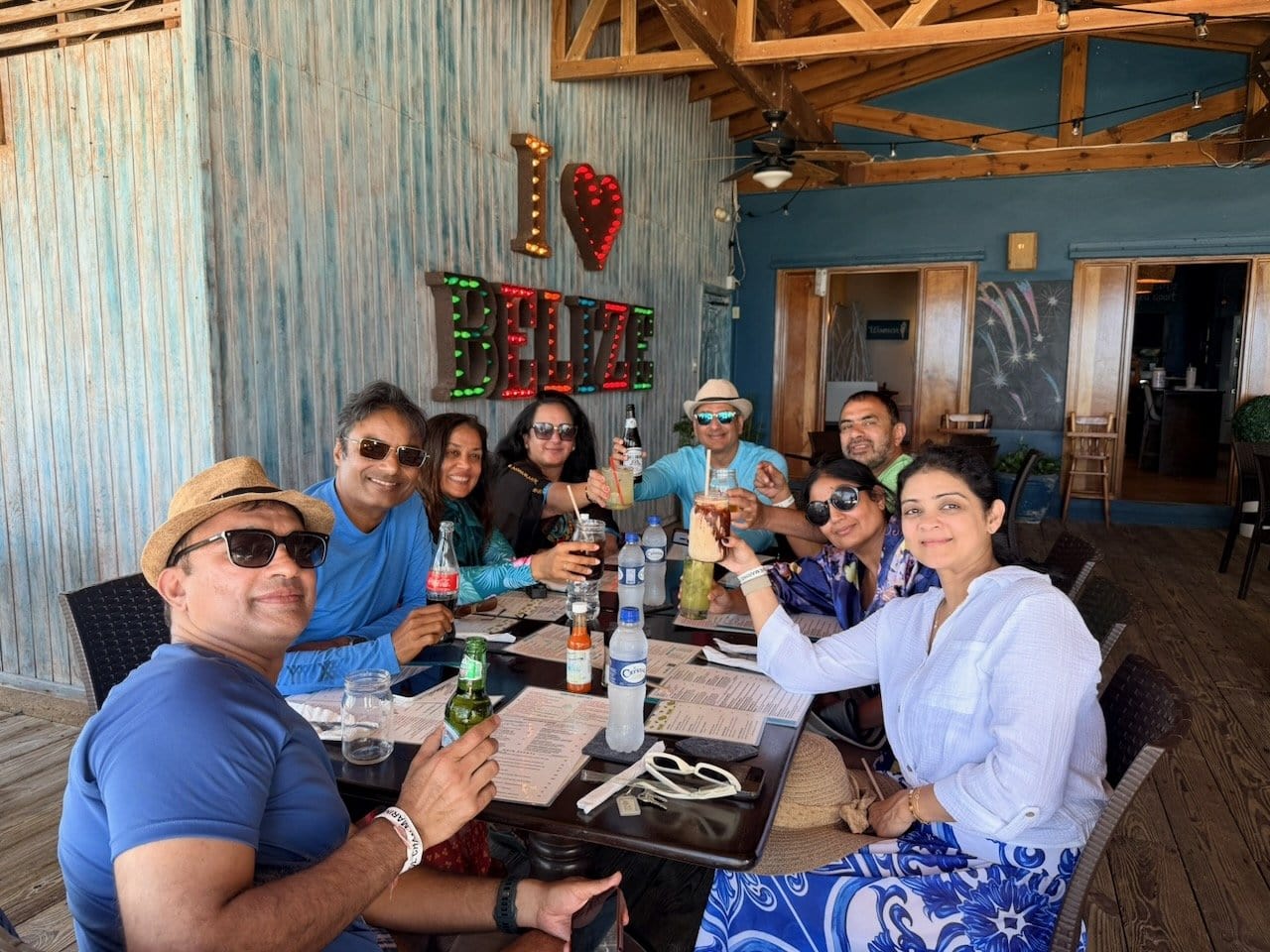 Group of eight friends at lunch at Blue Water Grill in San Pedro, with the I Love Belize neon sign behind them