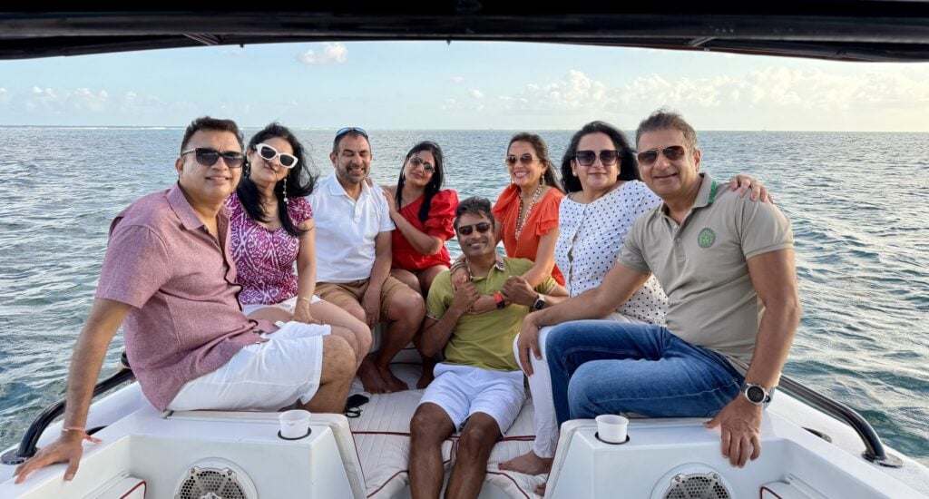 Group of eight friends on the bow of a chartered sunset cruise boat in San Pedro, Belize, at golden hour