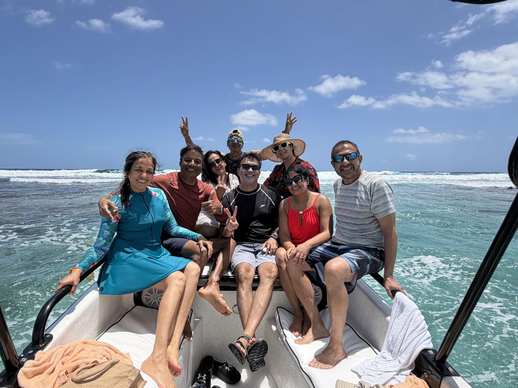 Group of seven friends on the back of the snorkeling boat at Mexico Rocks with breaking waves on the reef behind them