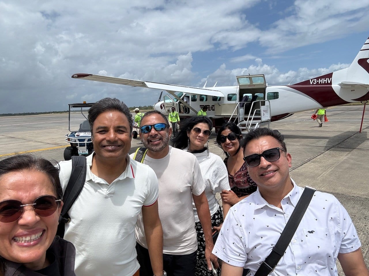 Six friends taking a selfie in front of the Tropic Air plane at Belize City airport