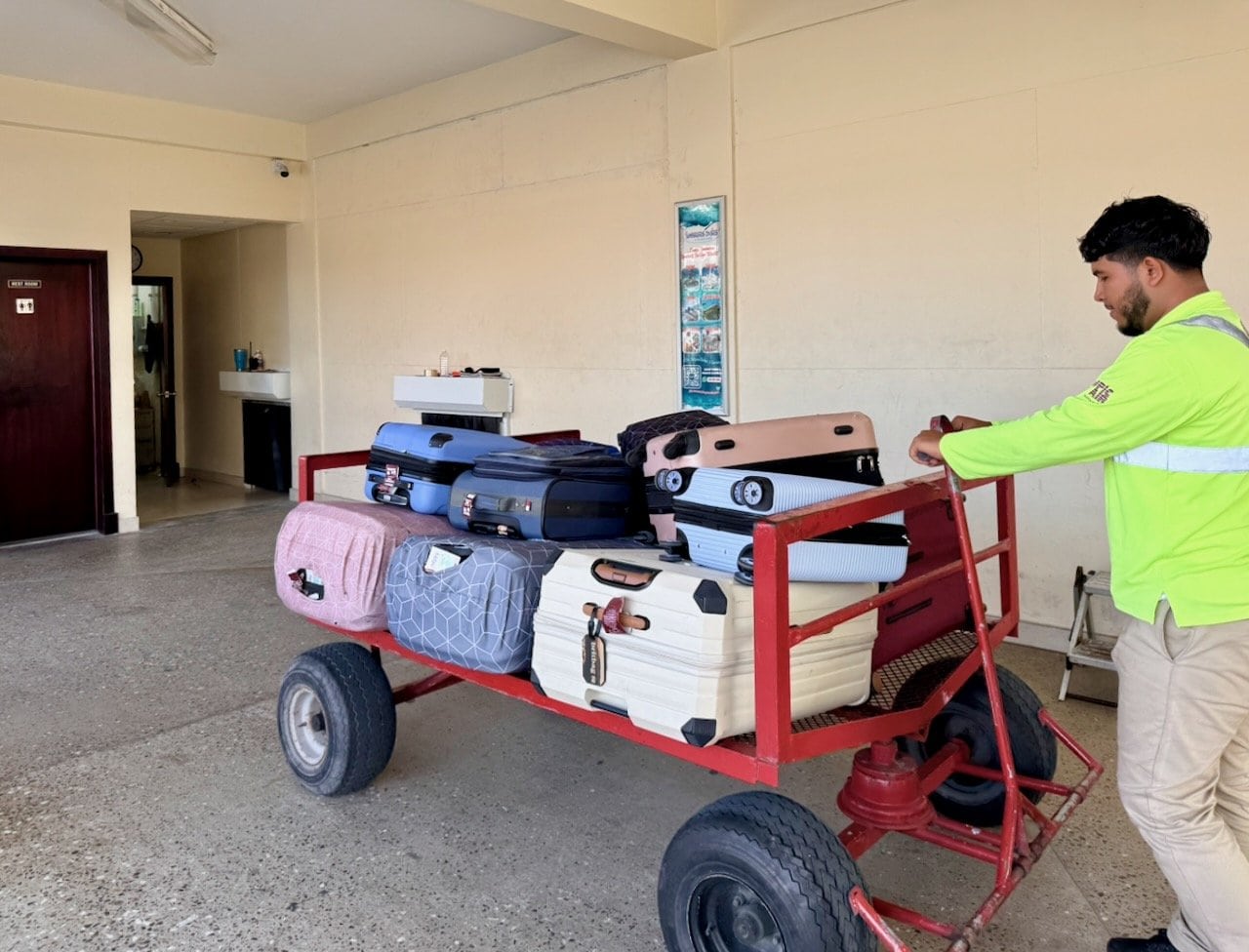 Airport staff member pushing a luggage cart through the small San Pedro Airport terminal on Ambergris Caye