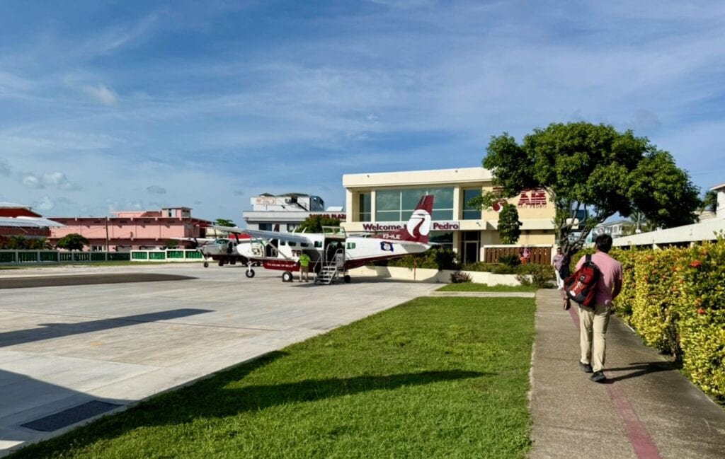 Tropic Air propeller plane on the tarmac at San Pedro Airport with the Welcome to San Pedro terminal building visible behind