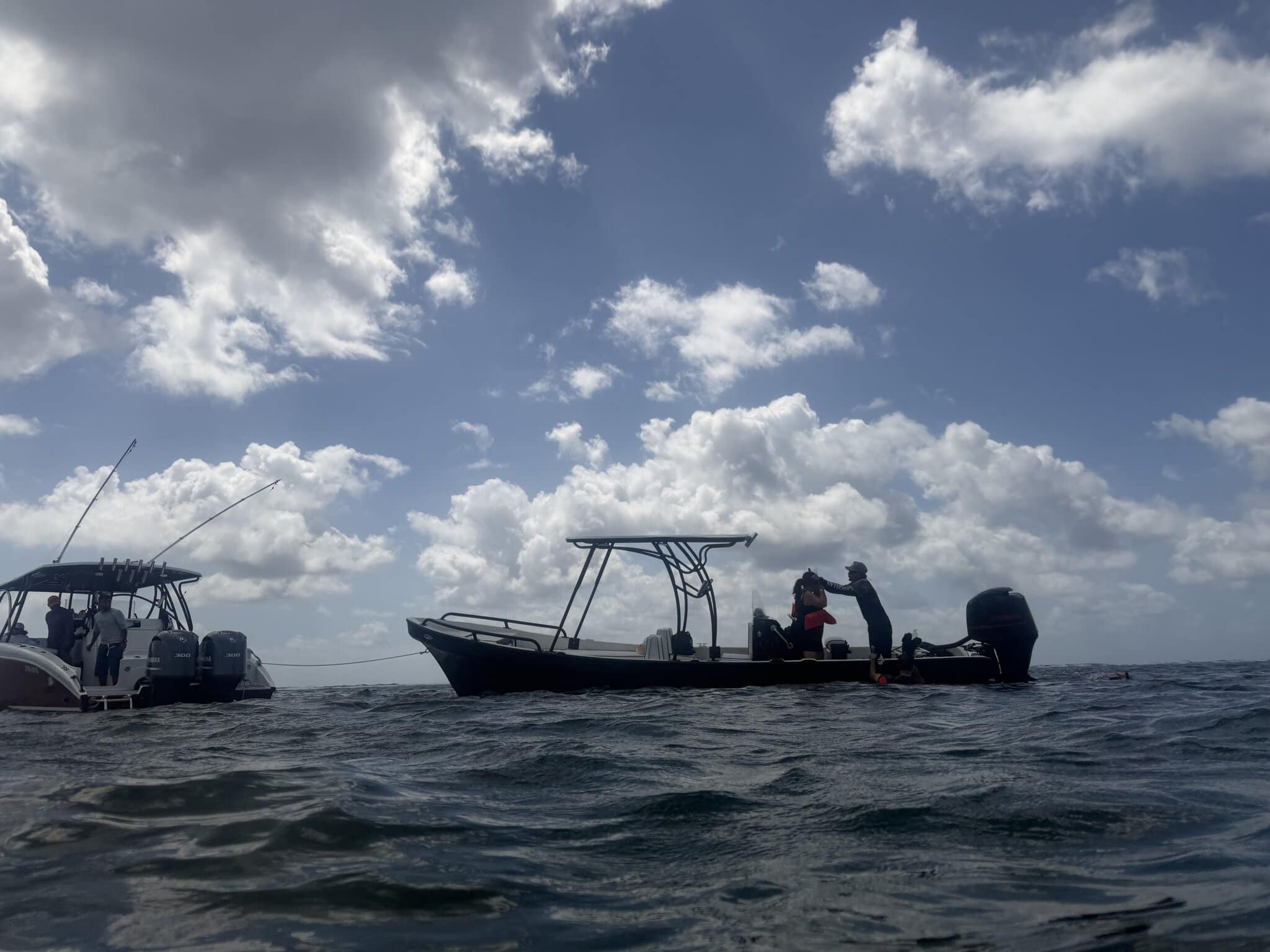 Two snorkeling tour boats anchored at the Belize Barrier Reef shot from water level with dramatic clouds overhead