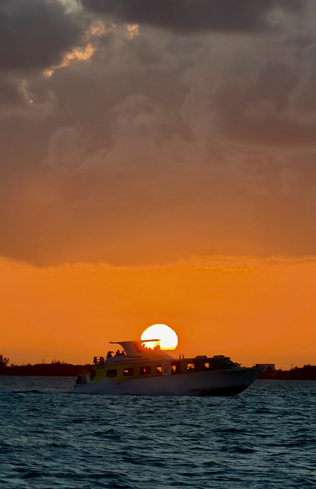 Boat silhouetted against a blazing orange and red sunset sky on the Caribbean Sea near San Pedro, Belize