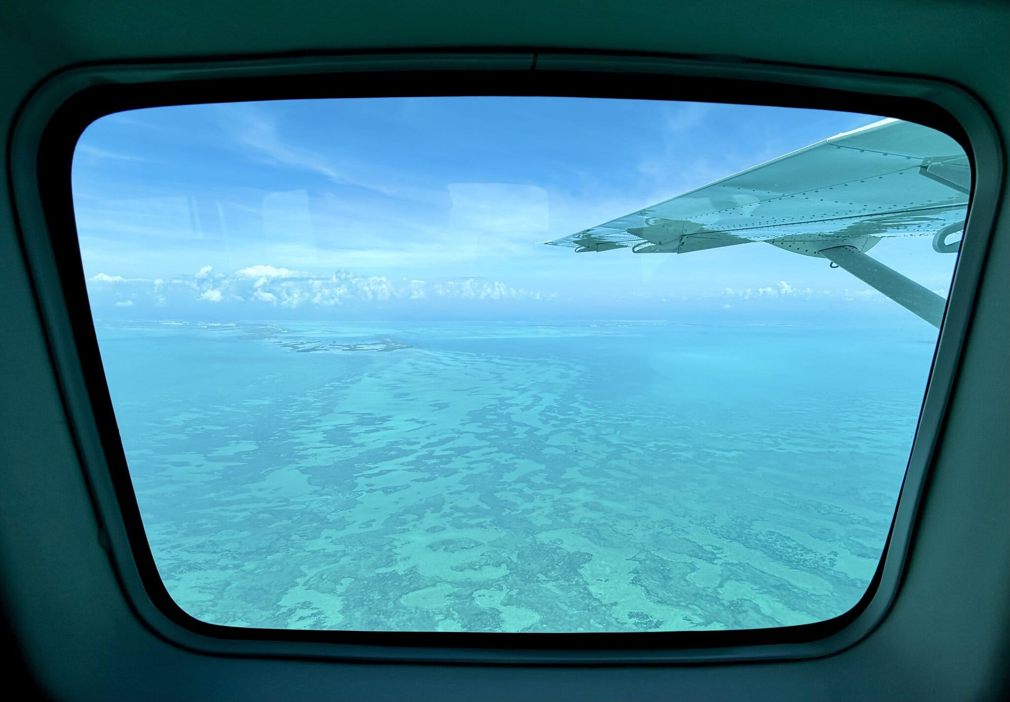 View through the Tropic Air plane window showing the Belize Barrier Reef below during the flight from Belize city to San Pedro