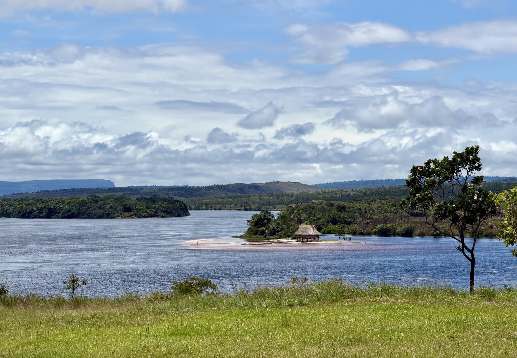 Wide calm lagoon with small thatched hut on sandbar in Canaima National Park Venezuela