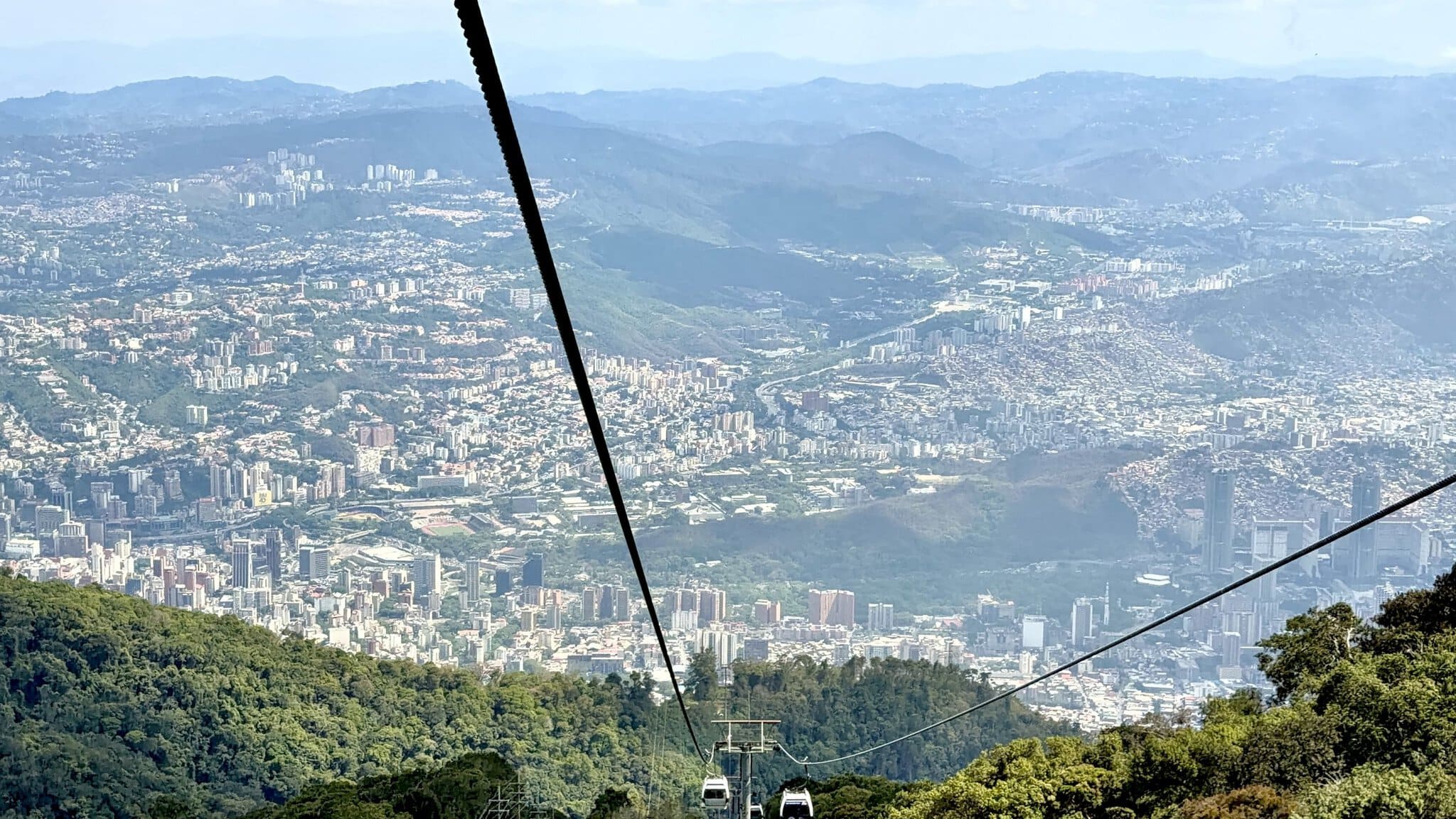 Aerial cable car view over sprawling Caracas city nestled between green mountain ranges