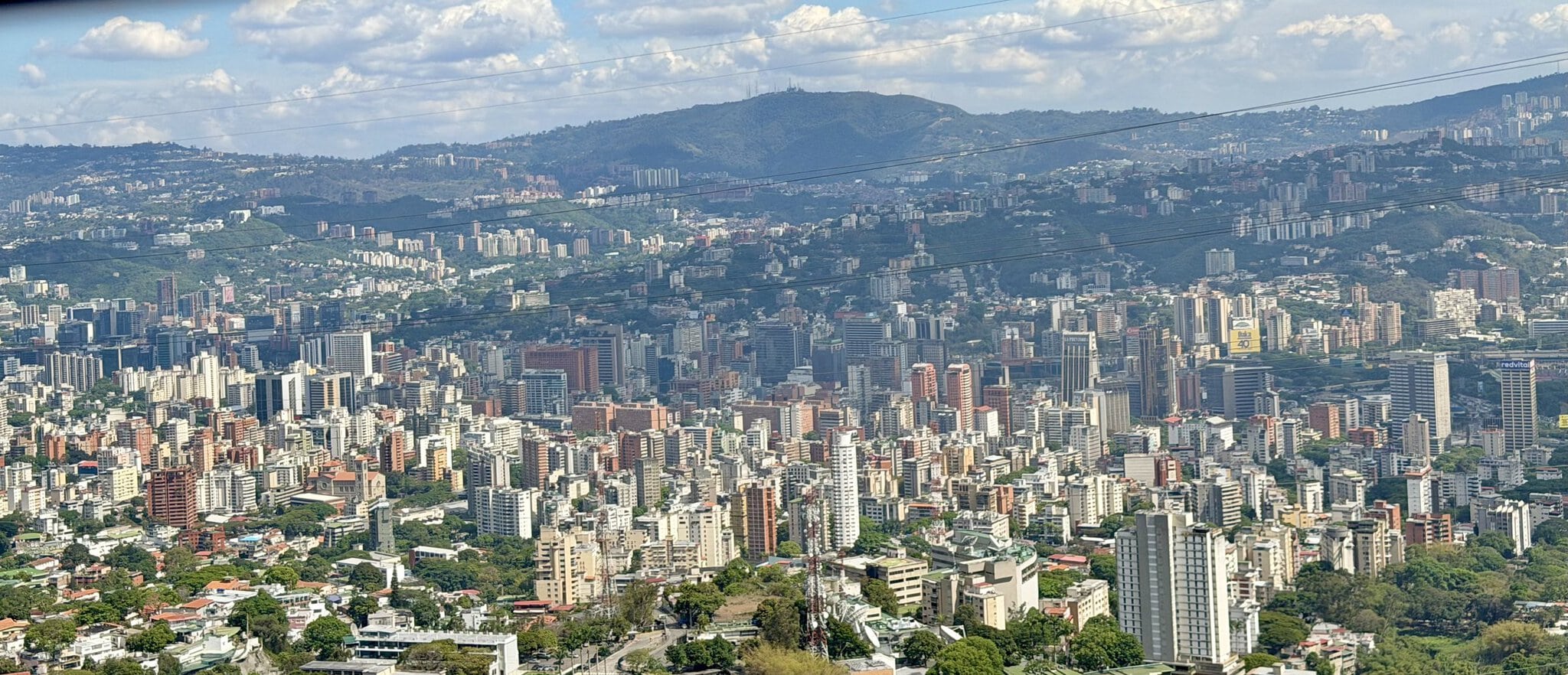 Aerial panoramic view of dense Caracas cityscape with green mountains in background