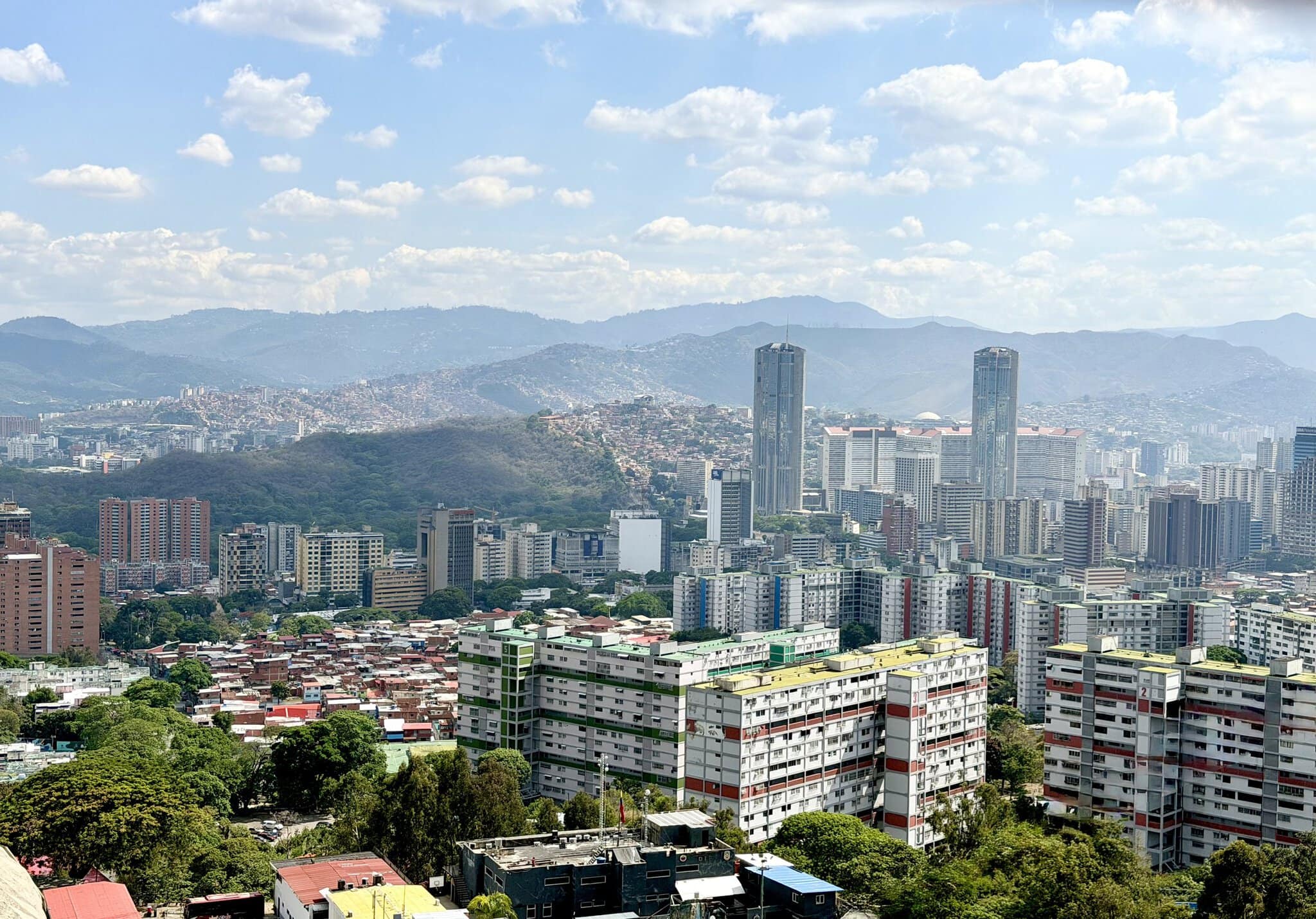 Caracas skyline with twin skyscrapers, colorful residential blocks, and green hills in background