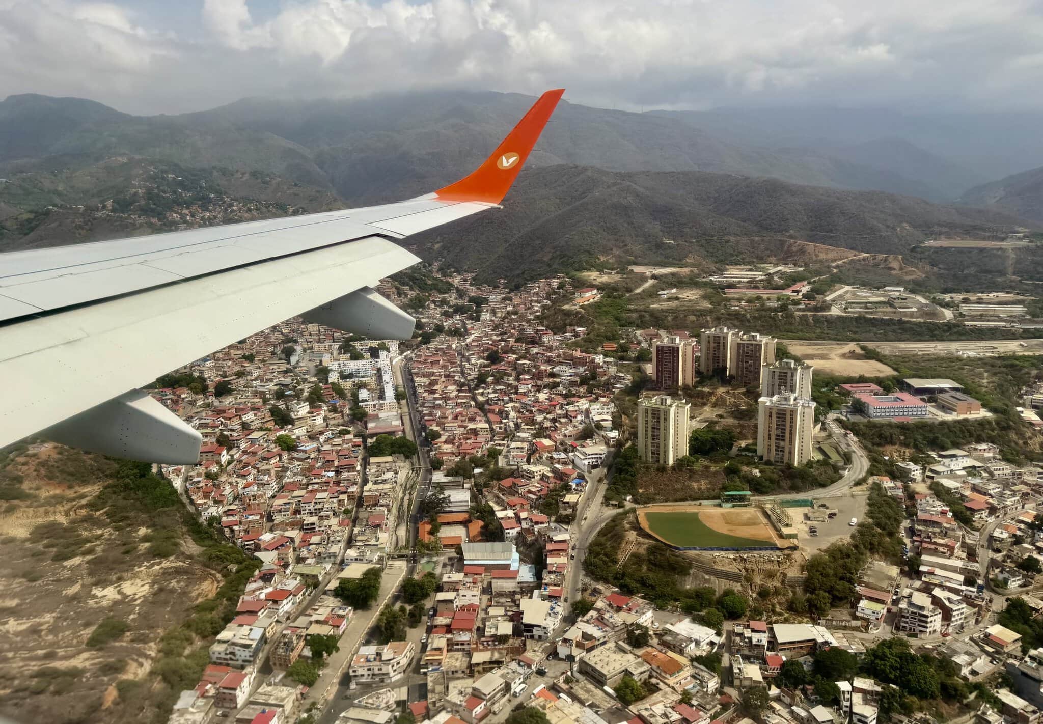 Aerial view of dense Caracas neighborhoods and mountains from Conviasa airplane window