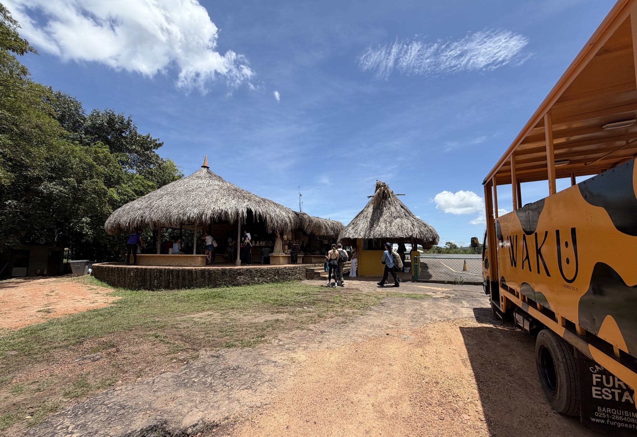Traditional thatched-roof huts at the Canaima airstrip with orange tour truck