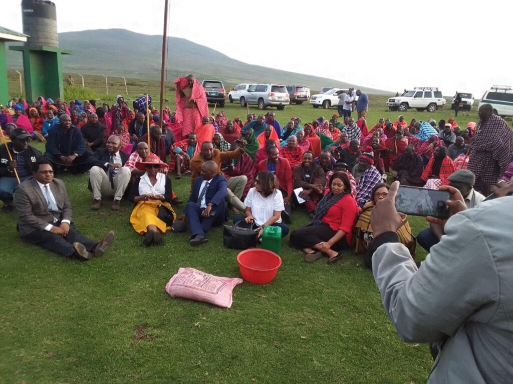 Officials and community members sit together on the grass in Ngorongoro, with a sample presented during the discussion